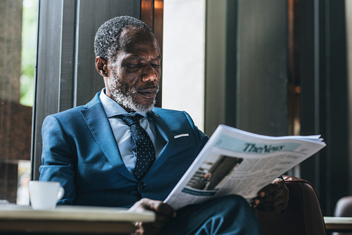 Elagant Businessman Reading Daily Newspaper at Cafe Man in suit sitting reading the newspaper