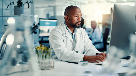 Man in lab coat working on a computer in busy lab